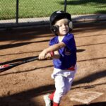 Young baseball player swinging a bat on the field.