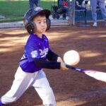 Young baseball player swings at a pitch during a game.