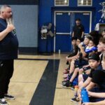 Coach addressing youth basketball team during practice.