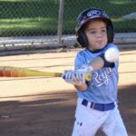 Young boy hitting a baseball during a game.