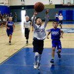 Young boy scoring a basketball shot during a game.