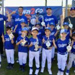 Youth baseball team proudly posing with trophies after a victorious game.