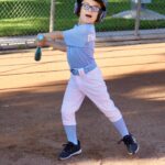 A young baseball player swings a bat on the field during practice.