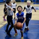Young basketball player aiming for a shot amidst defenders.