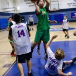 Youth basketball players compete intensely during a game on indoor court.