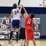 Two basketball players jump for the ball during a tip-off.