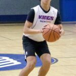 A basketball player in a Kings jersey prepares to shoot on an indoor court.