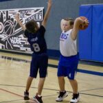 Two basketball players in action during a game on an indoor court.