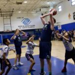 Youth basketball players compete during a game at an indoor court.