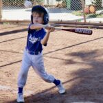 Young boy swinging a baseball bat on a field.