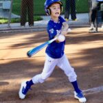 Young baseball player swings a bat during a game.