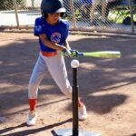 Young baseball player preparing to hit a ball off a tee.