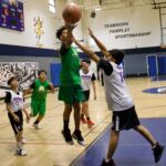 Youth basketball game with a player shooting the ball amid defenders.