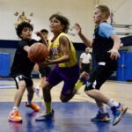 Young boys playing an intense basketball game indoors.