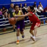 Youth basketball game with a player driving past a defender.