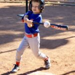 Young boy swinging a baseball bat during a game.