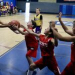 Basketball players compete intensely near the hoop during a game.