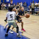 Young basketball players compete intensely in a gym game.
