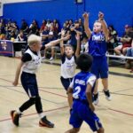Kids enthusiastically playing basketball in a gymnasium.