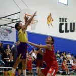 Youth basketball game with a player shooting over a defender.