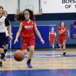 Young girl dribbling basketball during a game.