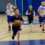 Young boys playing basketball in a gym.