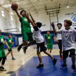 Youth basketball players compete intensely during a game in a gym.