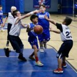 Young boys playing an intense basketball game indoors.