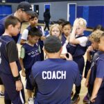 Coach instructing young baseball players during practice.