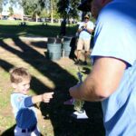 Young boy excitedly pointing at a trophy held by an adult.
