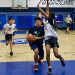 Youth basketball players in action during a game at a gym.