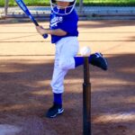 Young baseball player preparing to hit a ball off a tee.