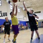 Youth basketball players compete intensely during a game in a gym.