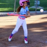 Young girl swinging a bat during a baseball game.