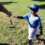 Young boy playing baseball, reaching for the bat.