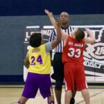 Two young basketball players jump for the ball at the start of a game.