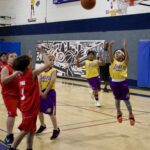 Youth basketball players compete intensely during a game in a gym.