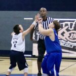 Two young basketball players reaching for the ball during a game tip-off.