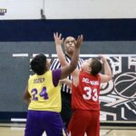 High school girls basketball players competing intensely for the ball near the hoop.