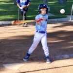 Young baseball player preparing to hit a pitch during a game.