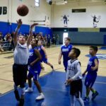 Kids playing basketball in a gym during a game.
