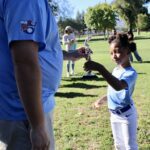 A child receives a small item from an adult outdoors.