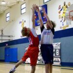 Two boys competing in a basketball game inside a gymnasium.