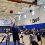 Young boys playing basketball in a gymnasium.