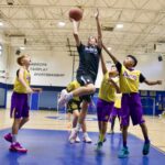 Youth basketball player leaps for a shot amid defenders.