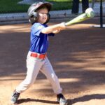 Young boy swinging a baseball bat during a game.